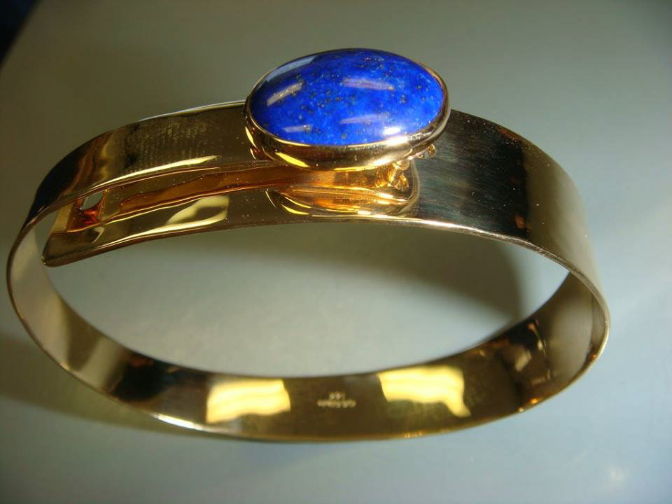 Wide yellow gold cuff with a bezel-set blue cabochon