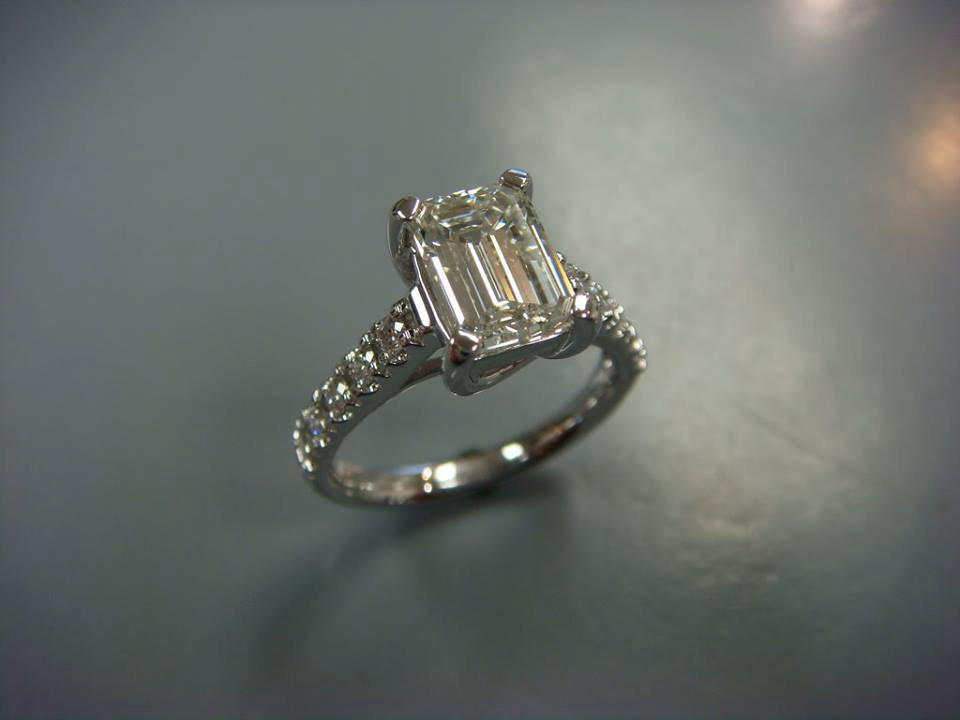Emerald-cut diamond solitaire engagement ring with a pavé white gold band