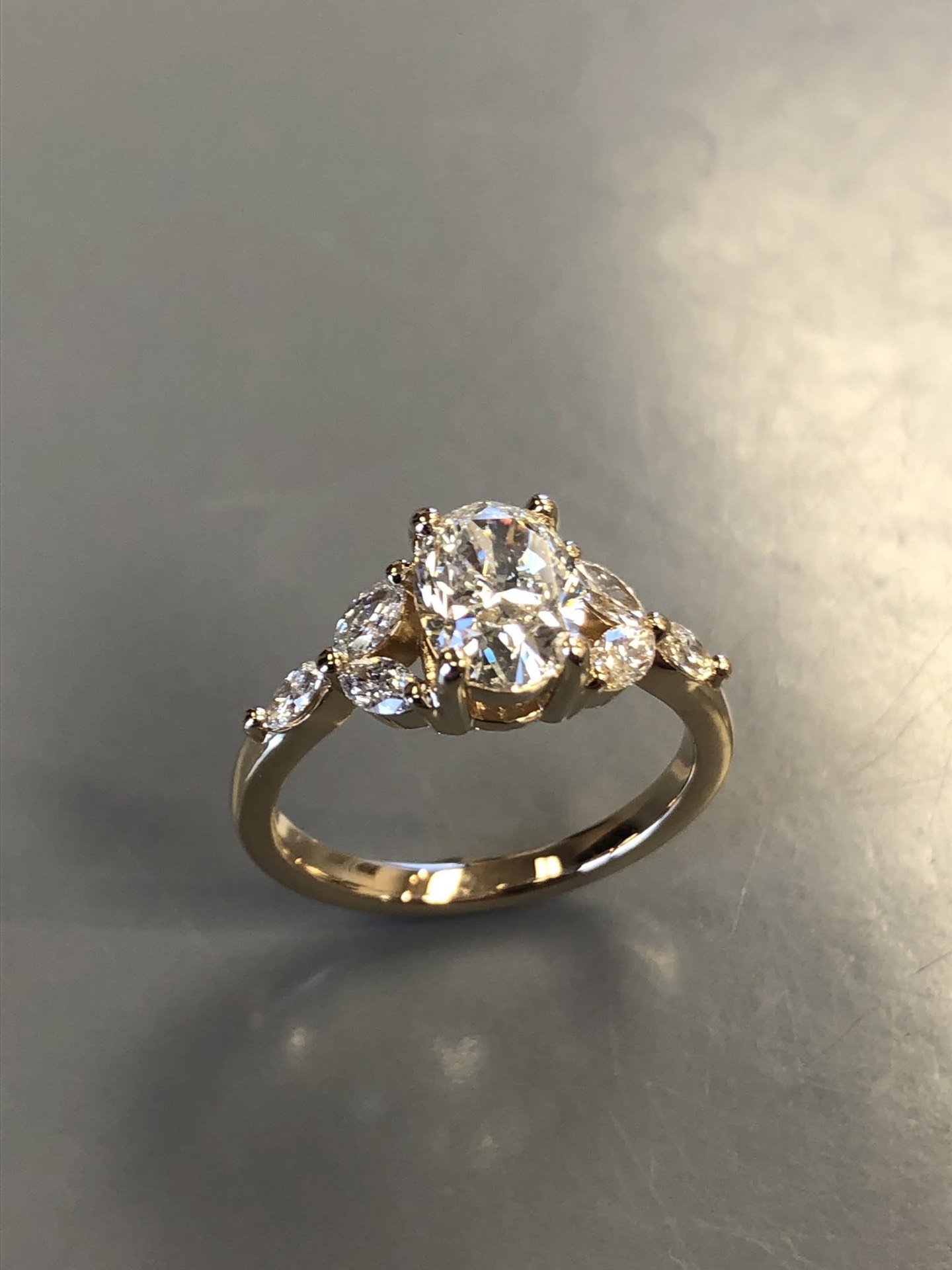Gold engagement ring with a round diamond and diamond side clusters