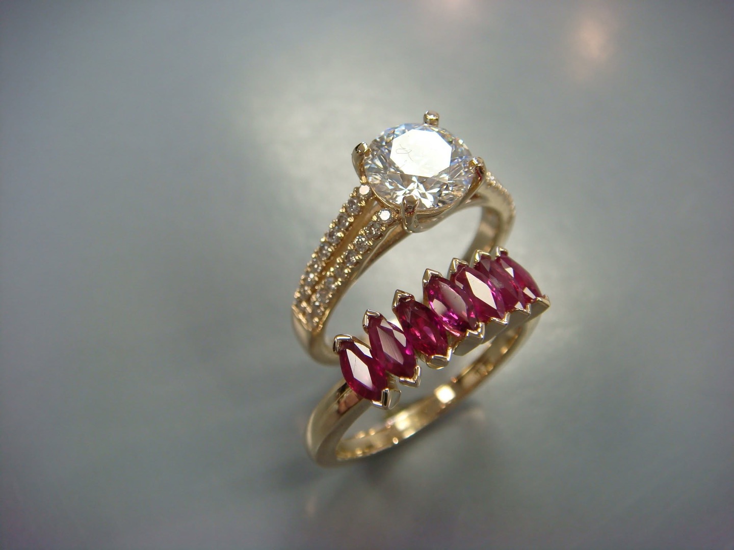 Gold diamond engagement ring paired with a band of marquise red gemstones