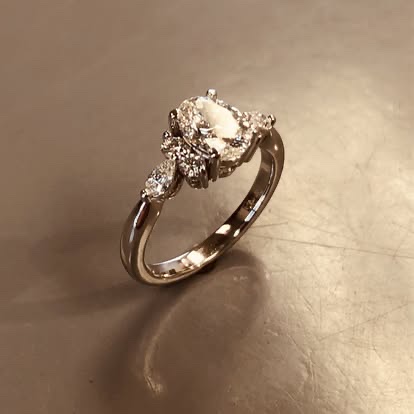 Gold engagement ring with a round diamond and leaf-style accents