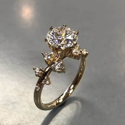 Gold engagement ring with a round diamond on a vine-style band