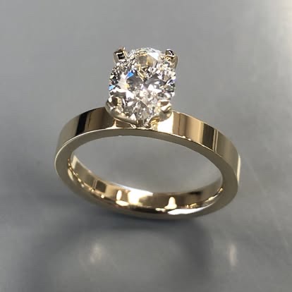 Gold oval diamond solitaire with a wide polished band