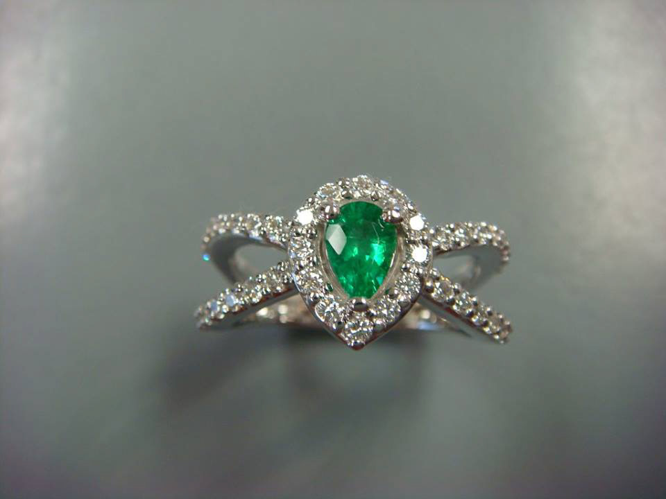 Pear-shaped emerald with a diamond halo on a crossover pavé band