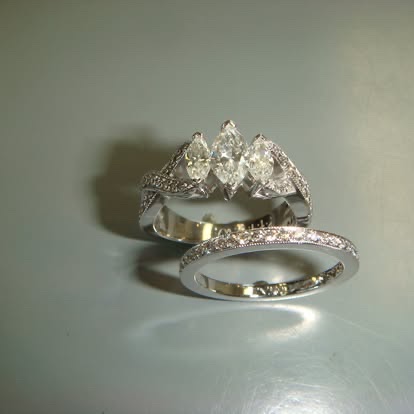 Two-tone engagement ring with a round diamond, pear side stones and a matching band