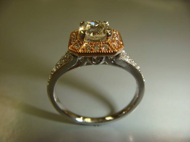 Two-tone engagement ring with a gold halo and a white gold pavé band