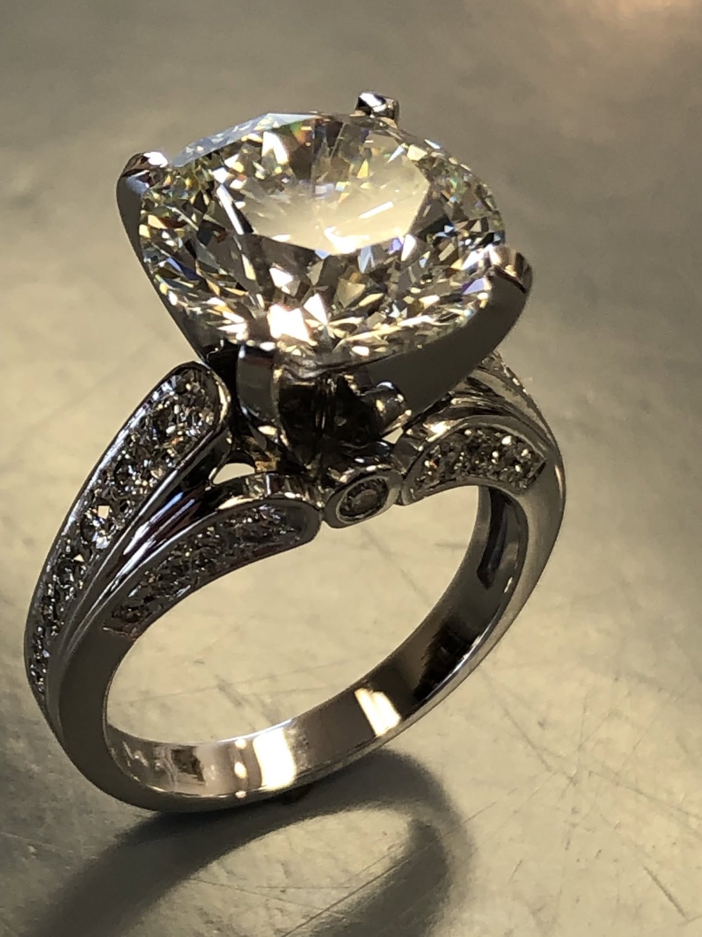 Large round diamond in a white gold cathedral setting with pavé and hand-engraved detail
