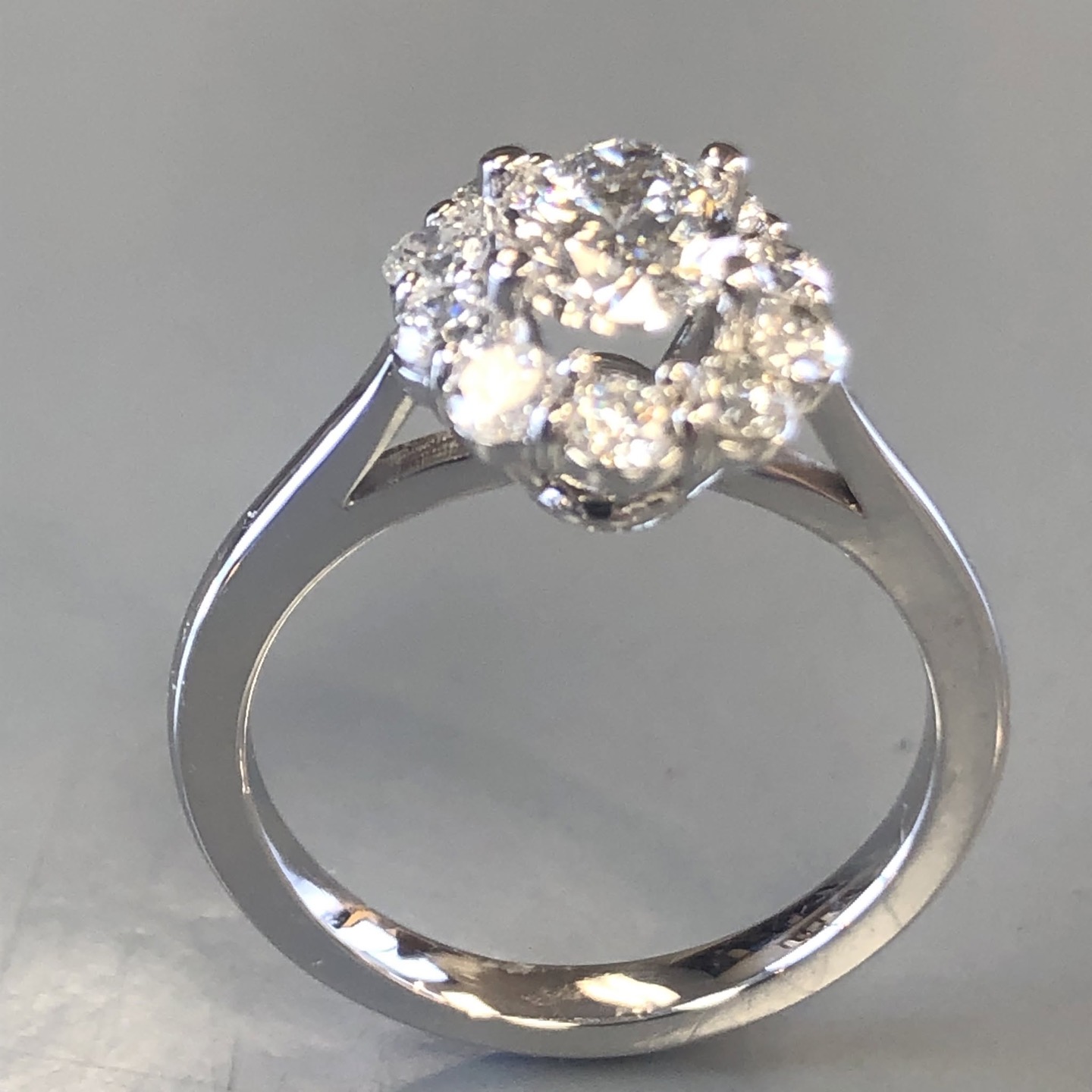 White gold engagement ring with a round diamond cluster in a high cathedral setting