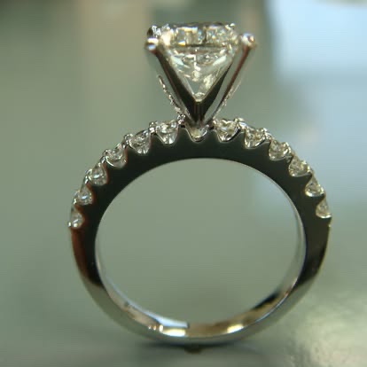 White gold diamond solitaire with a diamond-set band, shown upright