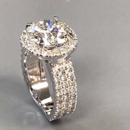 White gold halo engagement ring with a wide three-row pavé band