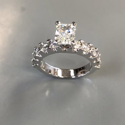White gold radiant-cut diamond ring with a scalloped pavé band