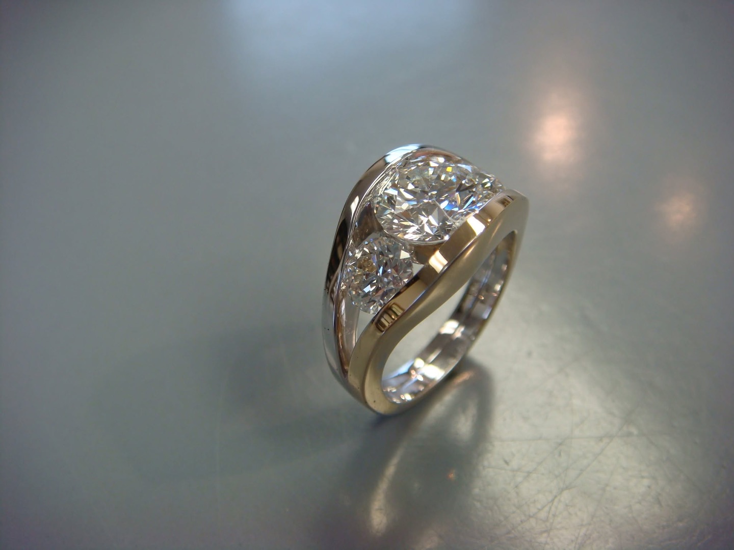 White gold ring with a round diamond set across a wide sculpted band