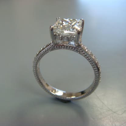 White gold solitaire with a milgrain and pavé band
