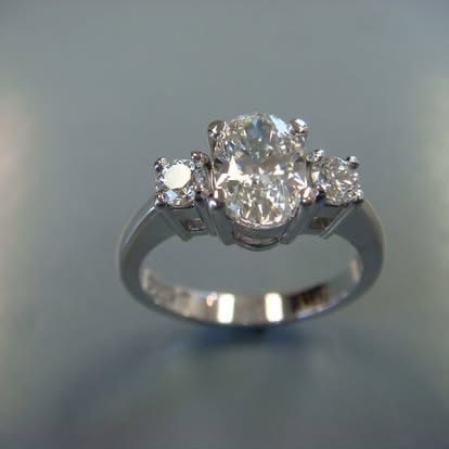 White gold three-stone ring with an oval center diamond