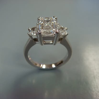 White gold three-stone ring with a radiant-cut center diamond