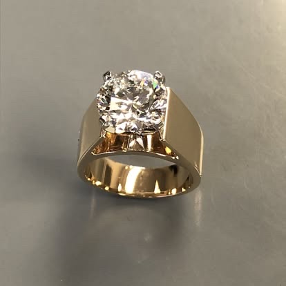 Wide yellow gold band with a round diamond solitaire