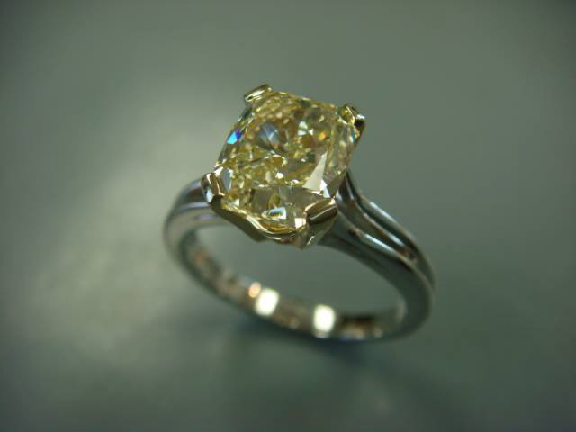 Cushion-cut yellow center stone set in a white gold engagement ring