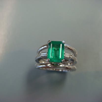 Emerald-cut green gemstone ring with a split white gold band