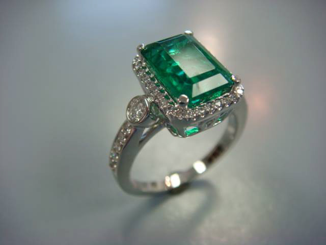 Emerald-cut emerald with a diamond halo in white gold