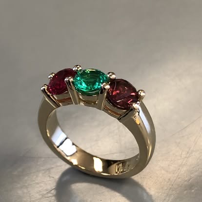 Gold three-stone ring with rubies and a green gemstone