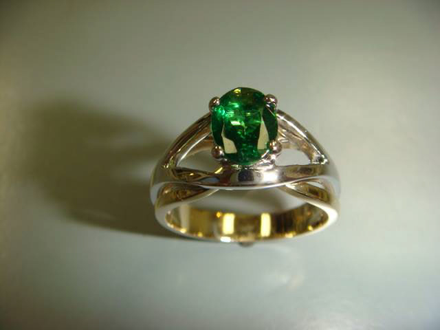 Oval green gemstone in a two-tone gold setting