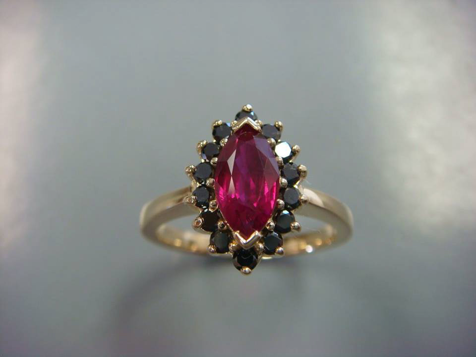 Marquise red gemstone with a halo of black stones in yellow gold
