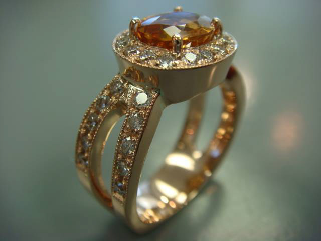 Oval orange gemstone with a diamond halo on a gold split band