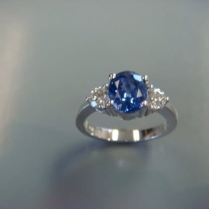Oval blue sapphire ring with diamond sides in white gold