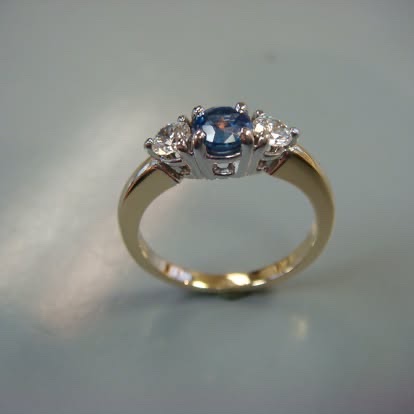 Oval blue sapphire three-stone ring in yellow gold