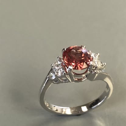 Oval pink-orange gemstone ring with diamond sides in white gold
