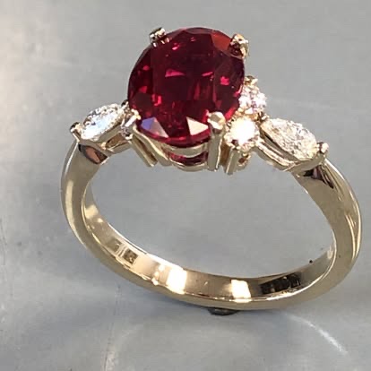Oval ruby ring with marquise diamond sides in yellow gold