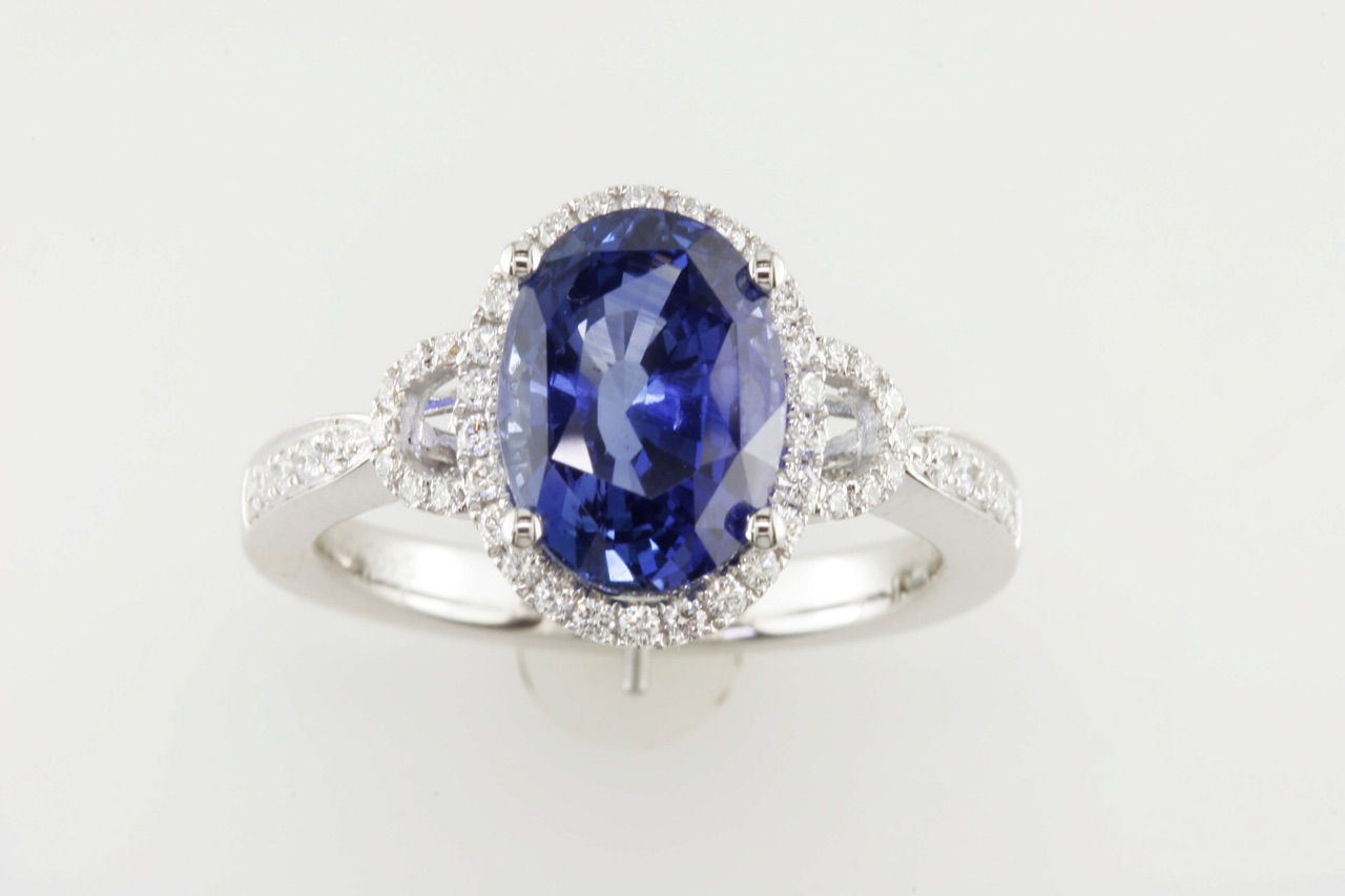 Oval blue sapphire ring with a diamond halo and pavé band