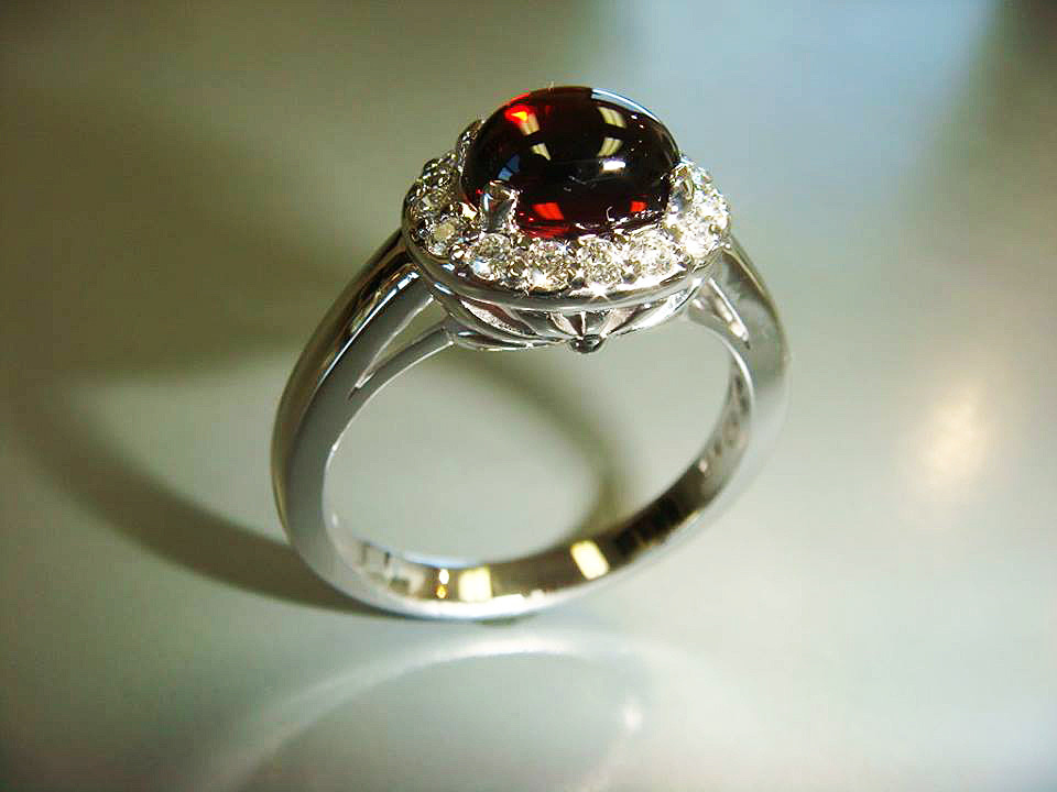 Round deep red gemstone ring with a diamond halo in white gold