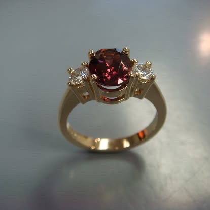 Round red gemstone ring with diamond sides in yellow gold