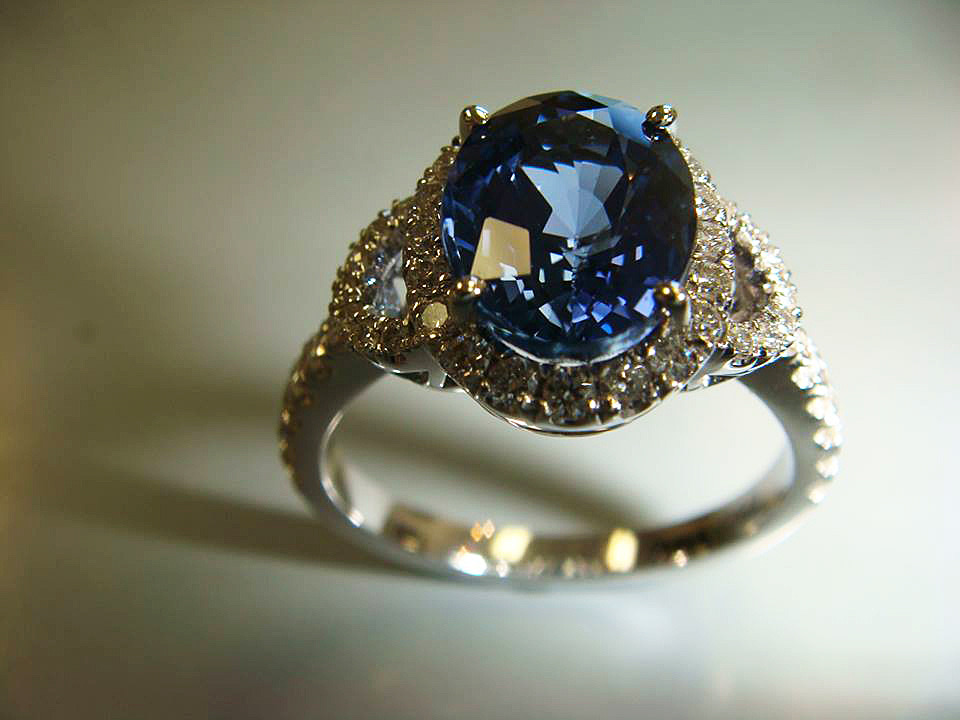 Oval blue sapphire with a diamond halo and side stones