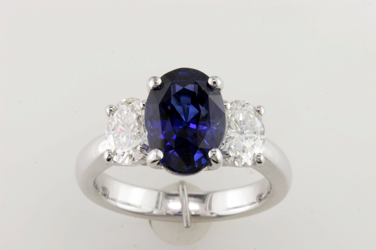 Oval blue sapphire ring flanked by two oval diamonds in white gold