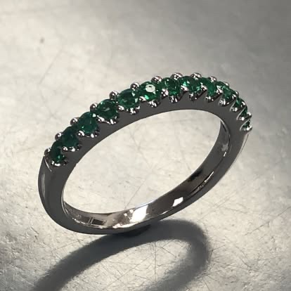 White gold band with a row of green gemstones