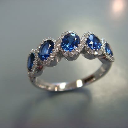 White gold ring with three oval sapphires in diamond halos