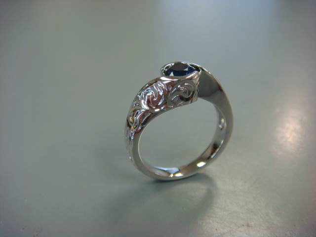 Hand-engraved white gold ring with a blue sapphire