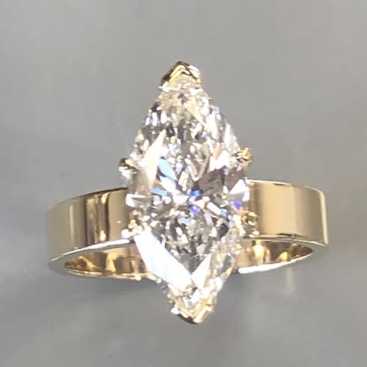 Large marquise diamond set across a wide yellow gold band