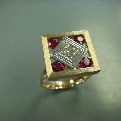 Square gold ring with a center diamond framed by rubies