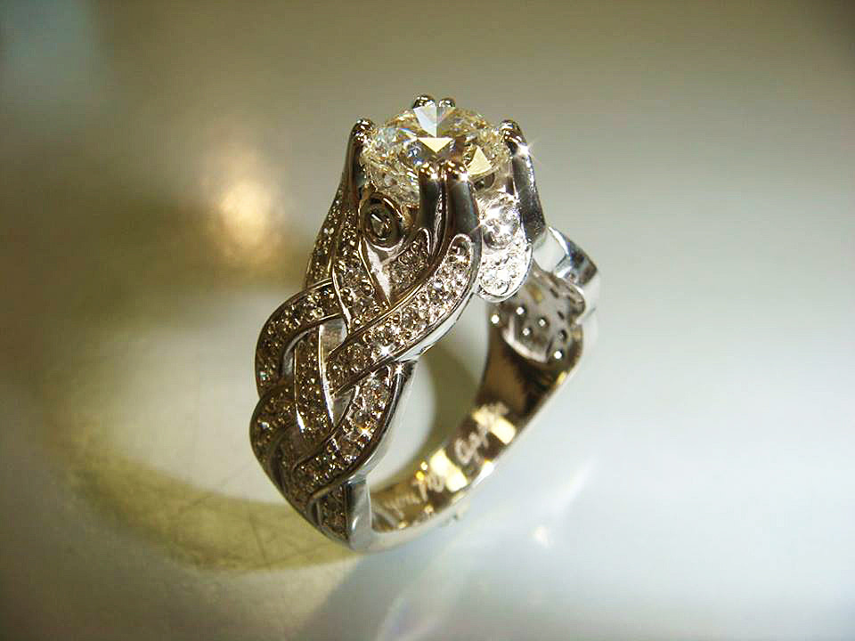 Woven white gold ring with pavé diamonds around a round center stone