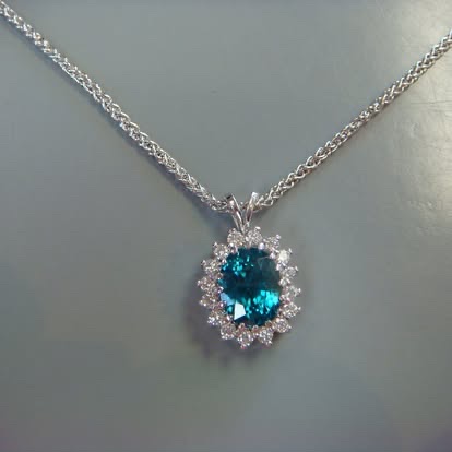 Blue-green gemstone pendant with a diamond halo in white gold