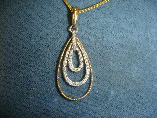 Double teardrop pendant outlined in diamonds in two-tone gold
