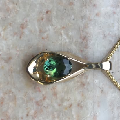 Gold pendant with a bezel-set green gemstone