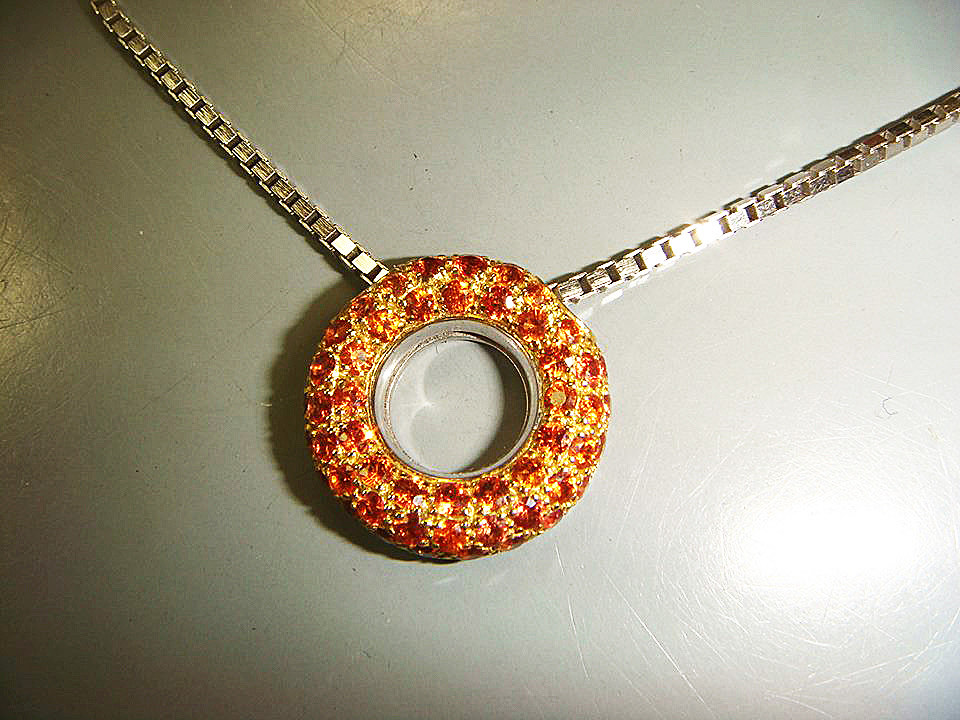 Open circle pendant set with orange gemstones on a white gold chain
