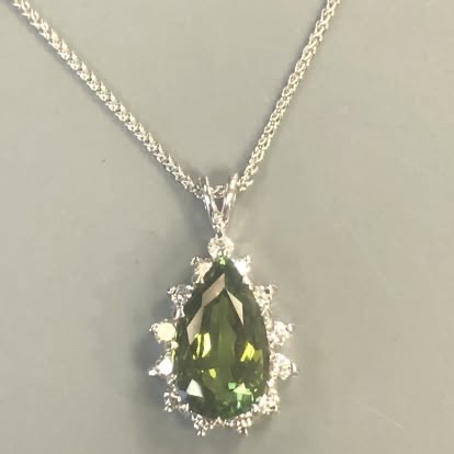 Pear-shaped green gemstone pendant with a diamond halo in white gold