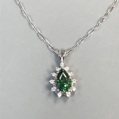 Pear-shaped green gemstone pendant with a diamond halo in white gold
