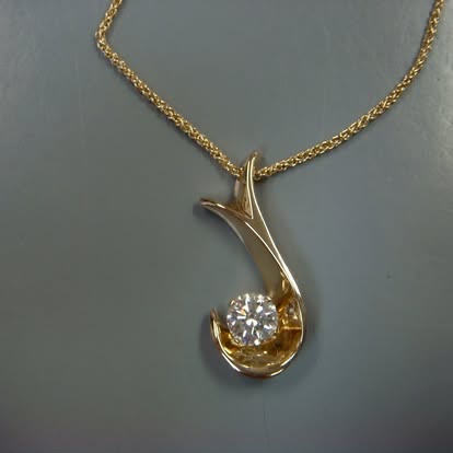 Sculpted gold pendant cradling a round diamond