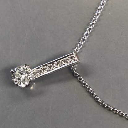 White gold bar pendant with a round diamond and pavé accents